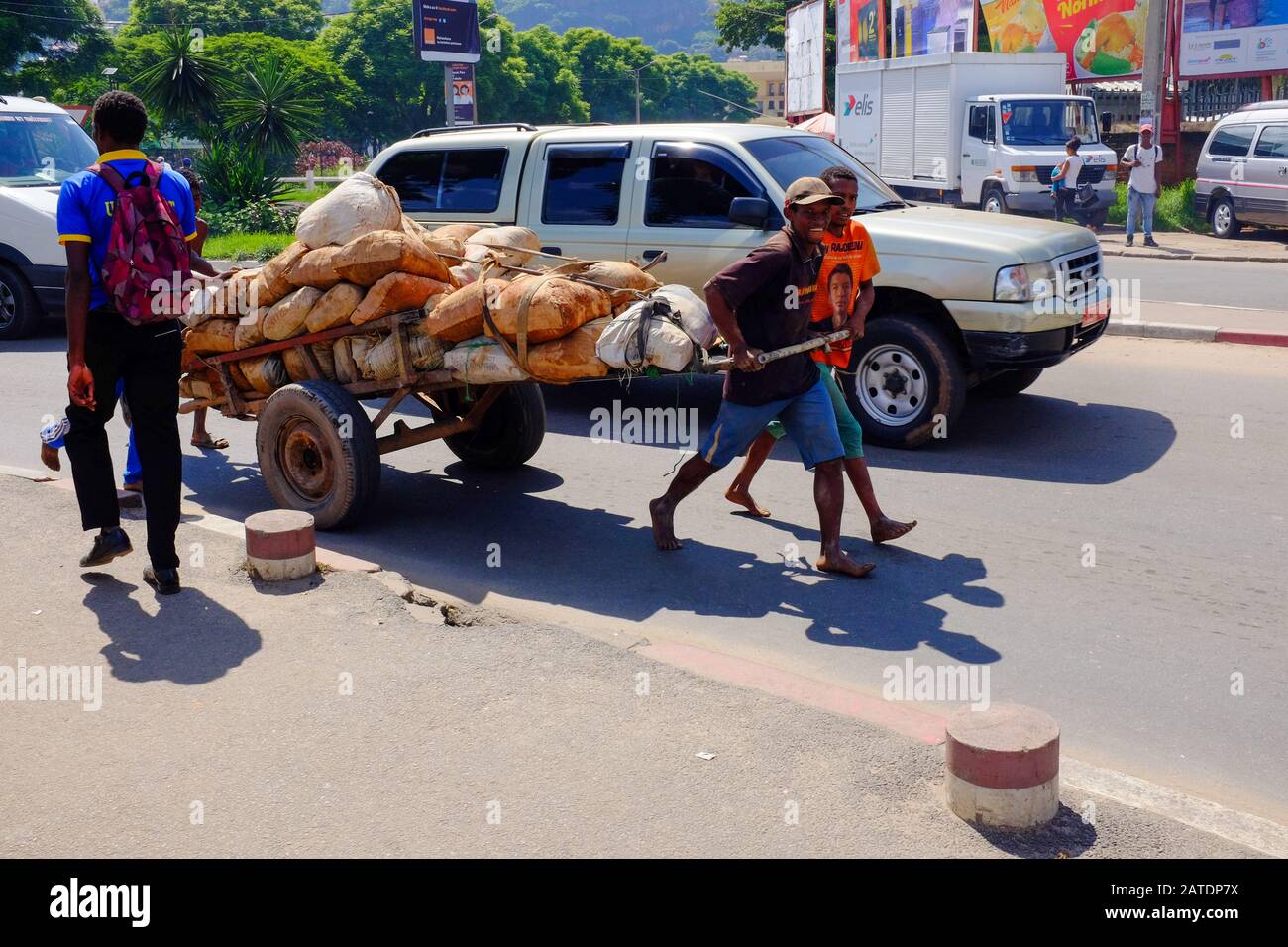 Two young men pull a hand-drawn cart through the streets of Antananarivo, the capital of Madagascar, one of the poorest countries in Africa. Stock Photo