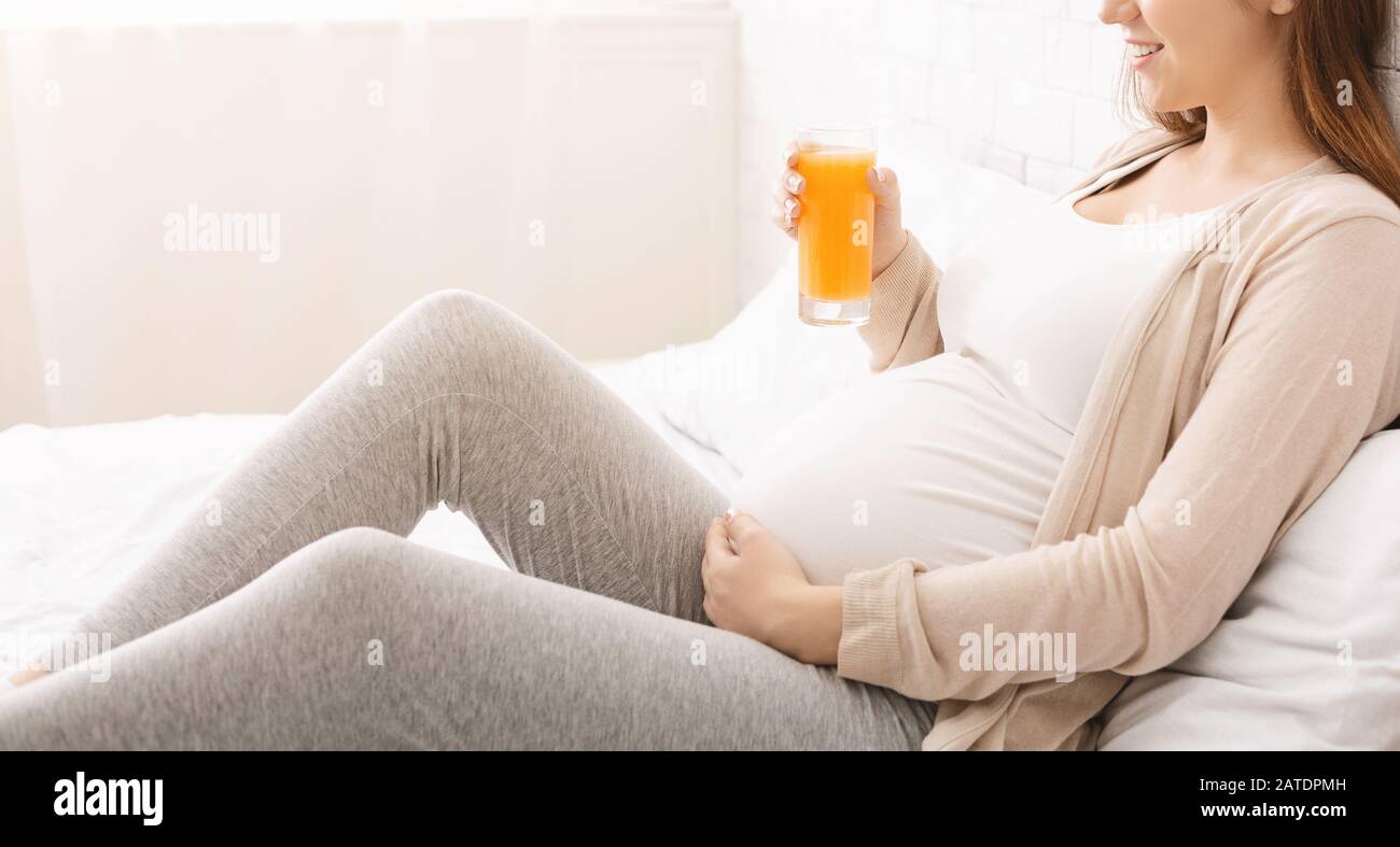 Pregnant lady drinking orange juice in bed, panorama Stock Photo Alamy