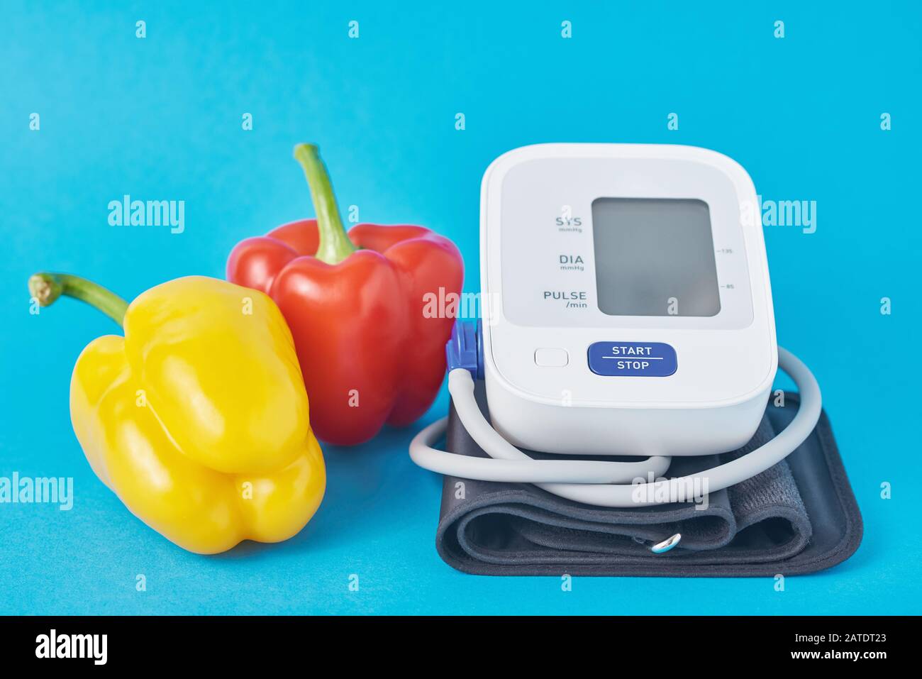 Digital blood pressure monitor and fresh vegetables pepper on blue
