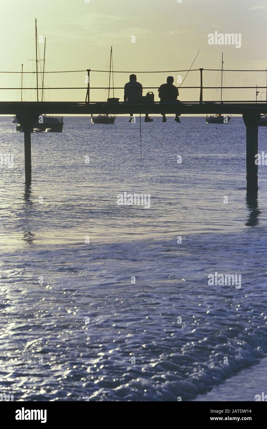 Bajan men fishing from a wooden pier. Barbados. Caribbean. West Indies Stock Photo