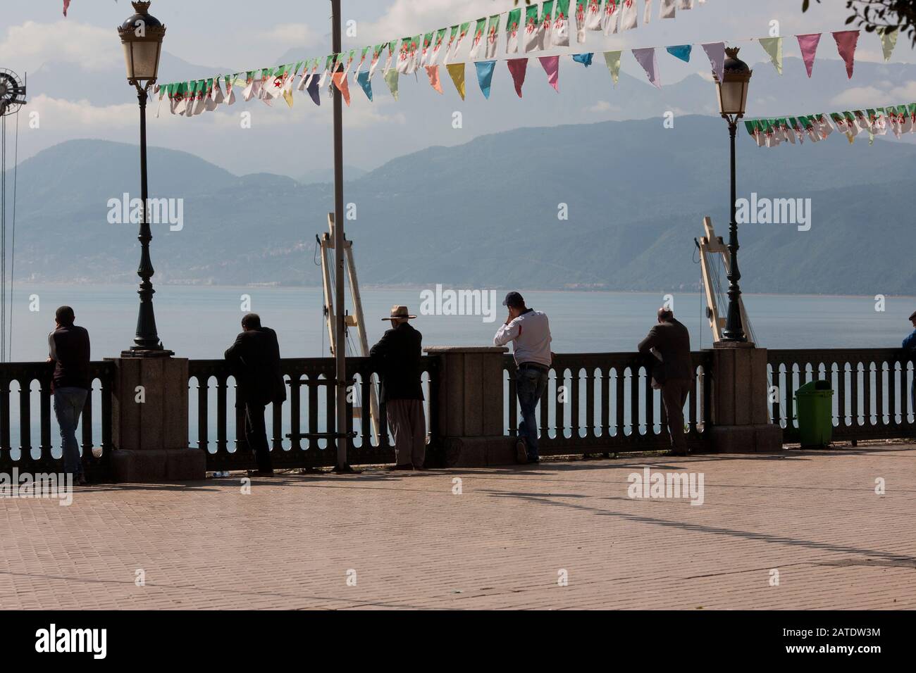 Men stand against the old french balustrades overlooking the port of Bejaia, the port city on Algeria's northern Mediterranean coast. Stock Photo