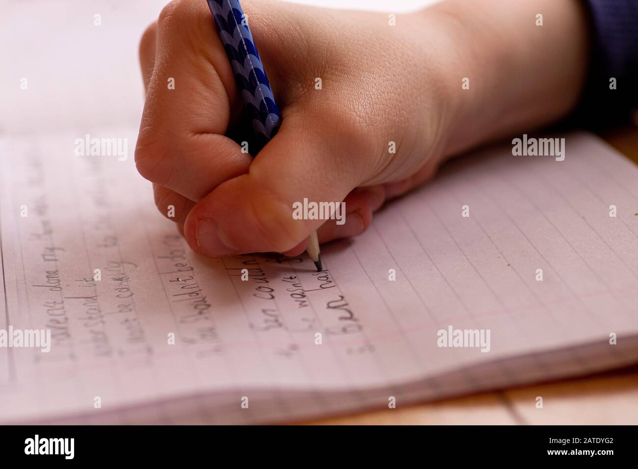 Child doing homework, writing lines and sentences with pencil Stock Photo