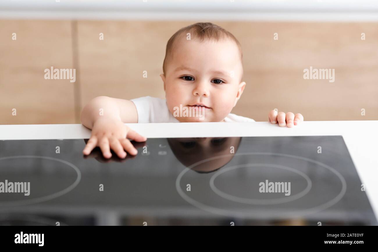 Alone curious baby touching hot electric cooktop Stock Photo