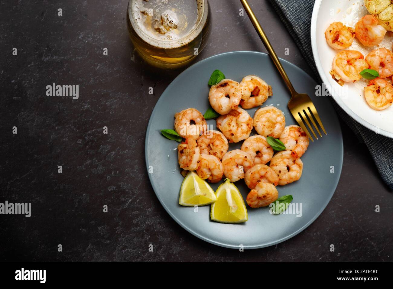 Top view of fried king prawns in a plate with glass of beer on black background Stock Photo