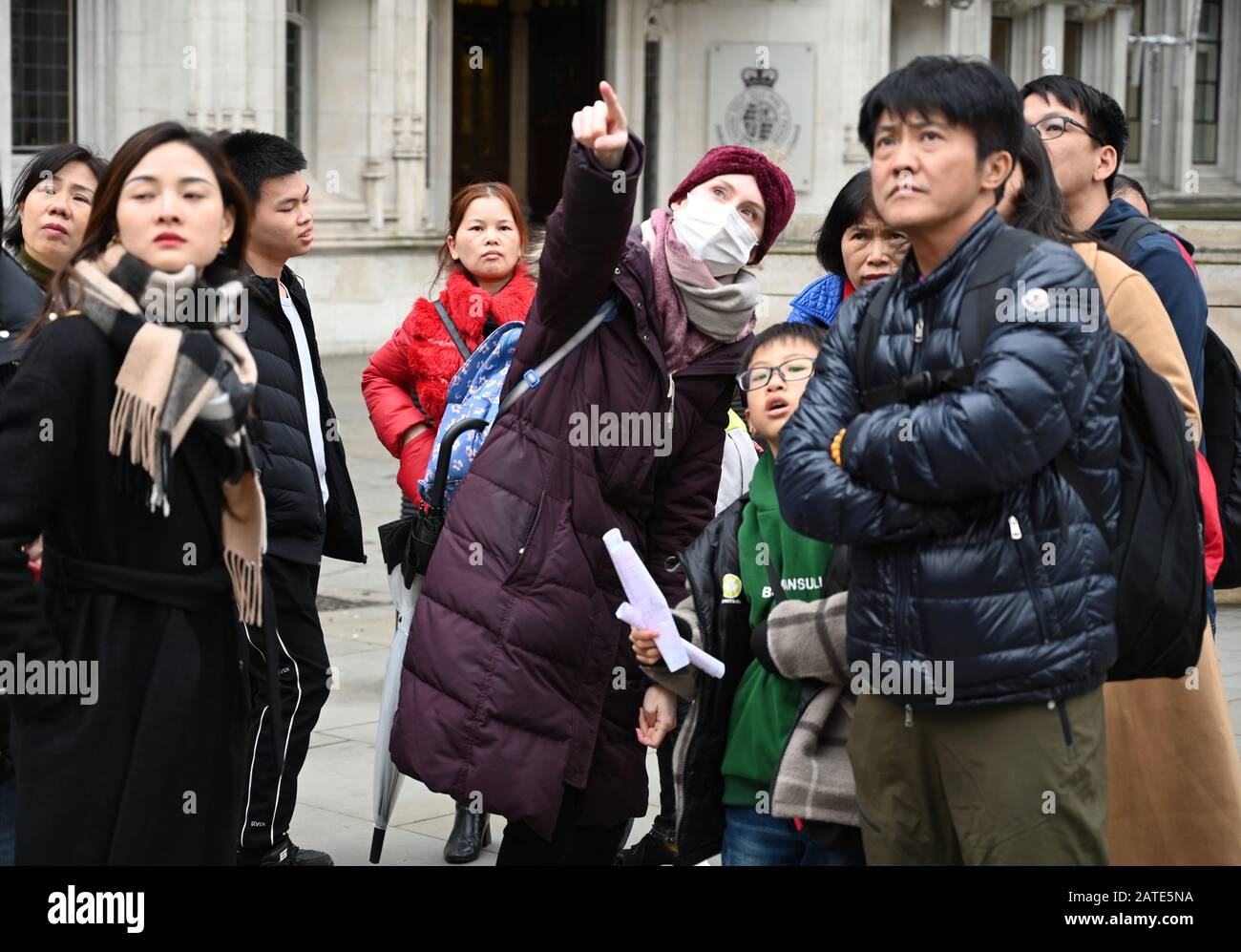 A tour guide wearing a face mask gives a talk on London's Heritage to a group of Chinese Tourists. Parliament Square, London. UK Stock Photo