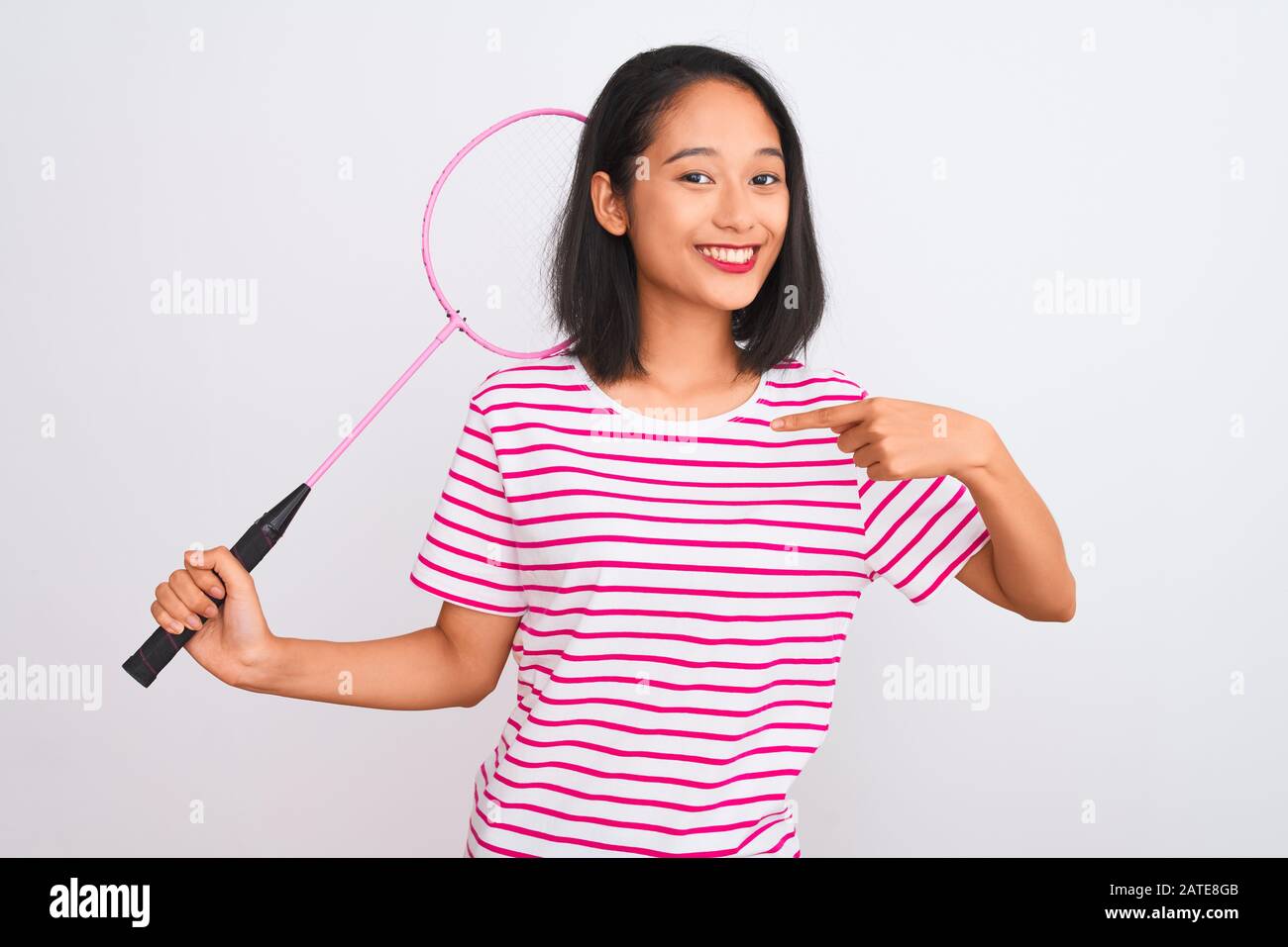 Young beautiful chinese woman holding badminton racket over isolated
