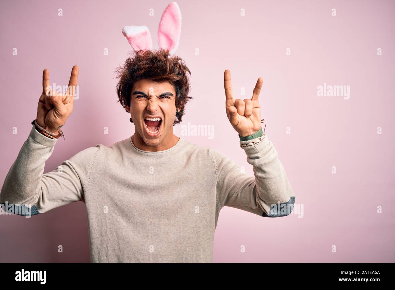 Young handsome man holding easter rabbit ears standing over isolated ...