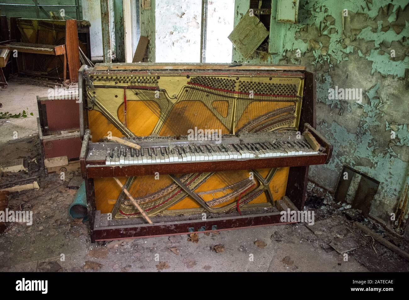 Old ruined grand piano in a concert hall in the city of Pripyat: collapsed  rows of chairs, green walls, a broken wooden stage, a zone of radioactive d  Stock Photo - Alamy