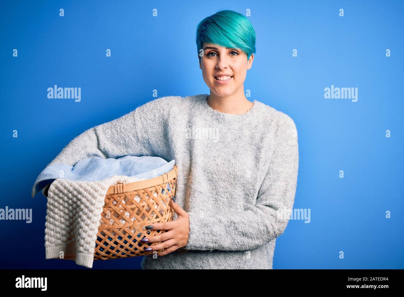 Young woman with blue fashion hair doing domestic chores holding wicker ...