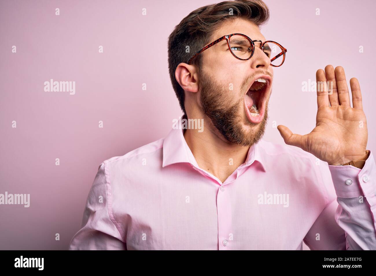 Young handsome blond man with beard and blue eyes wearing pink shirt ...