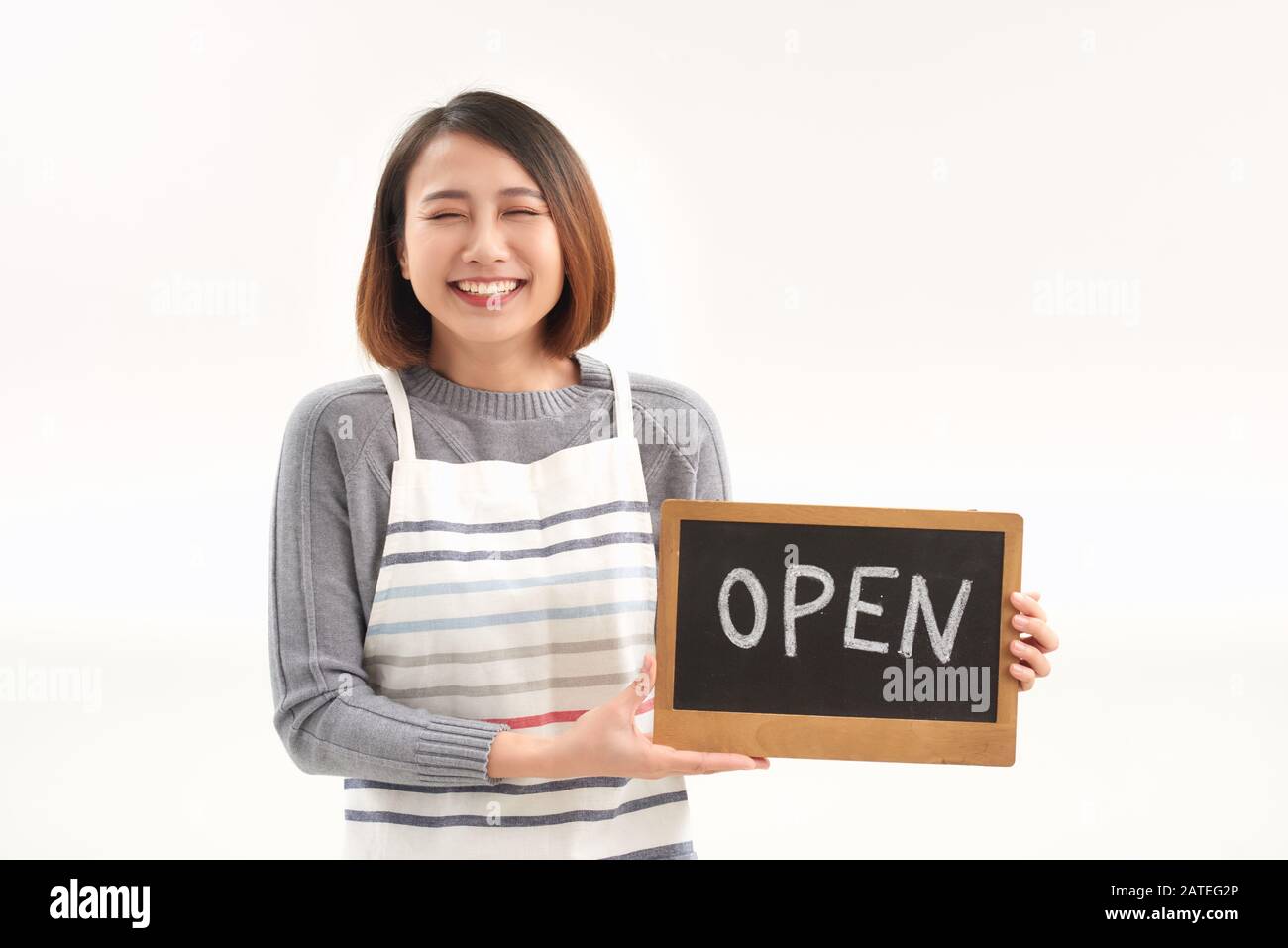 Portrait of young woman holding up an open signboard on white background Stock Photo