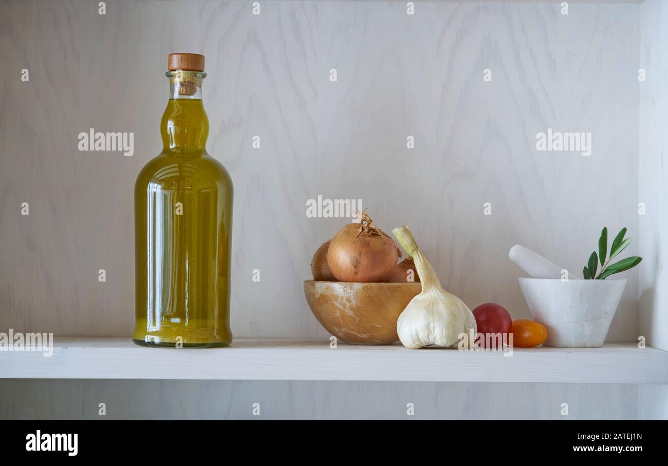 beautiful glass bottle of healthy organic cooking oil, which can also be olive oil, on a white wall shelf in a Mediterranean style, surrounded by heal Stock Photo
