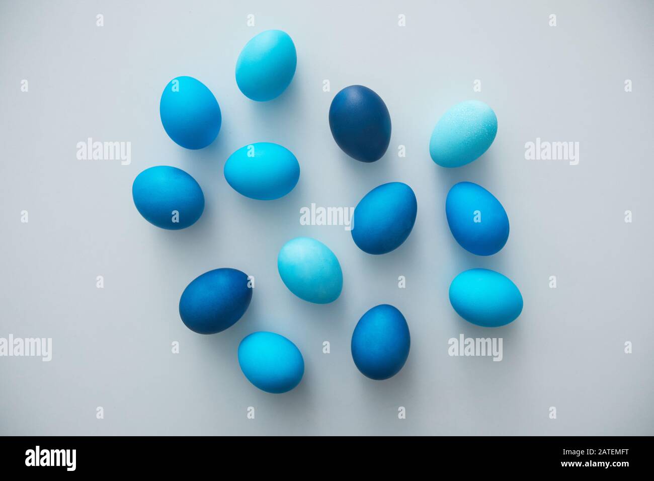 Above view of hand-painted blue Easter eggs arranged in minimal composition on white background, copy space Stock Photo