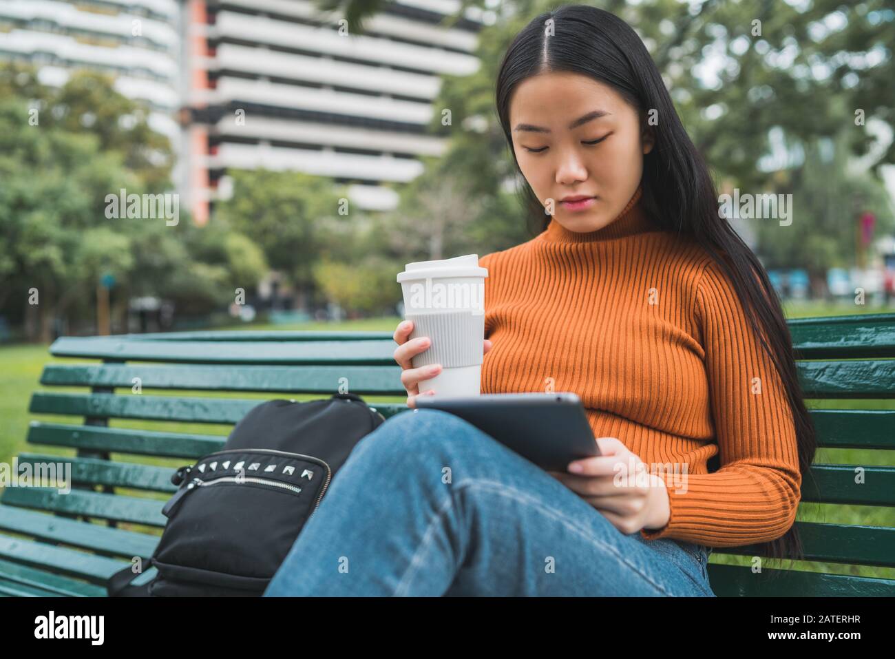 Portrait of young Asian woman using her digital tablet while holding a ...