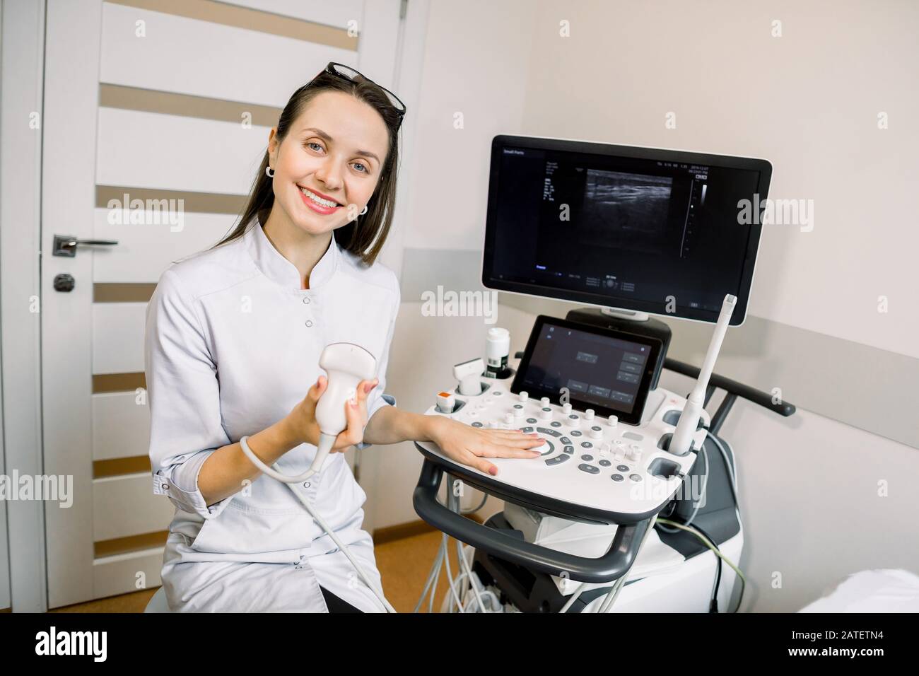 Professional young woman doctor sonographer sitting nearby modern  ultrasound scanner machine and smiling Stock Photo - Alamy