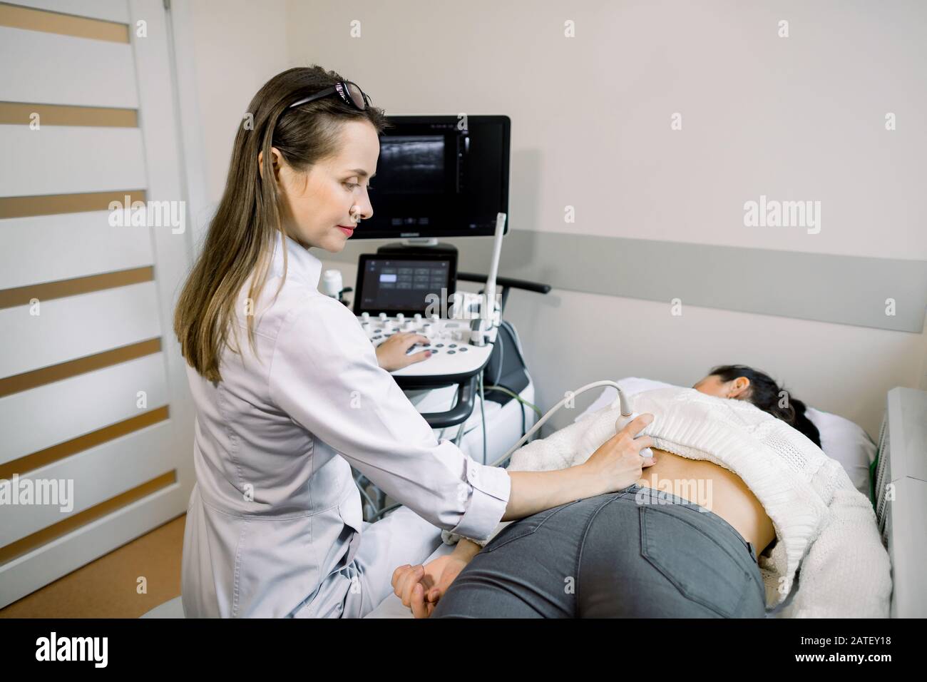 Ultrasound in physical therapy. Young woman therapist using ultrasound scanner on female patient lower back. Back and kidney ultrasound. Stock Photo