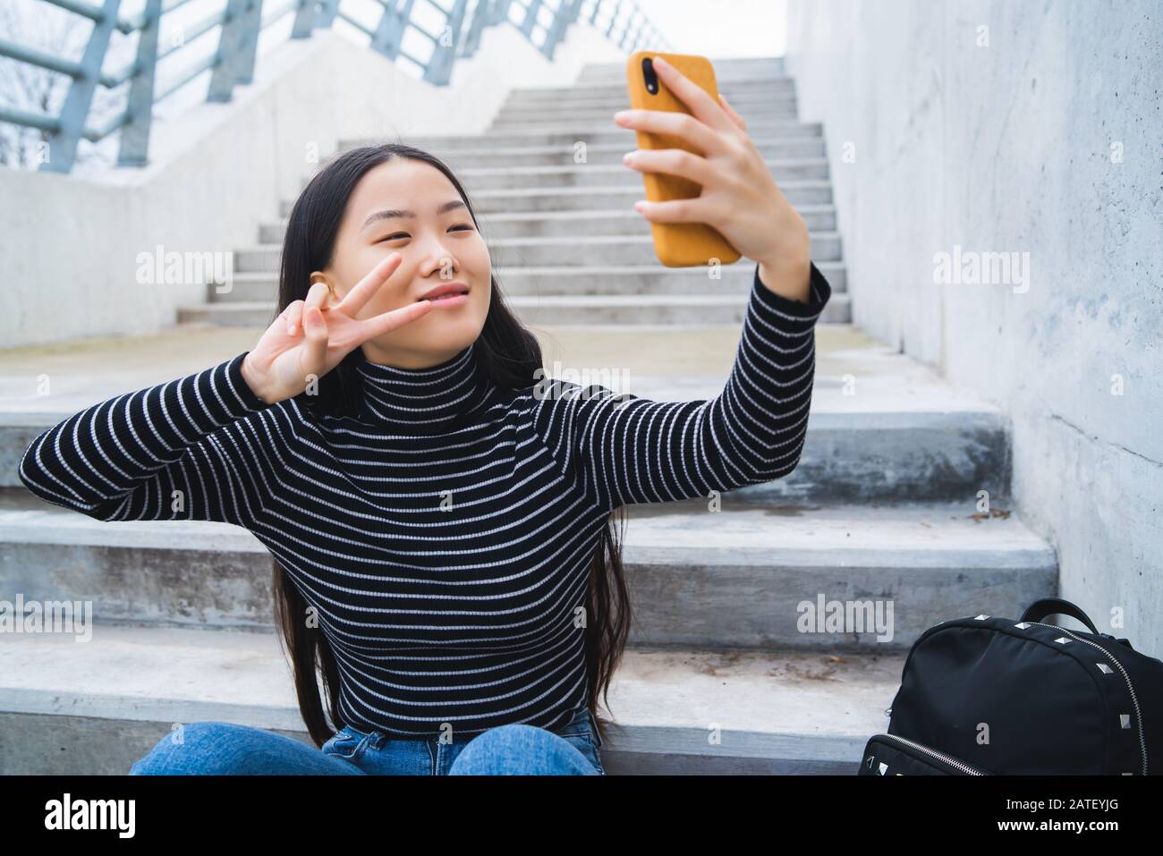 Portrait of young beautiful Asian woman taking a selfie with her mobile ...