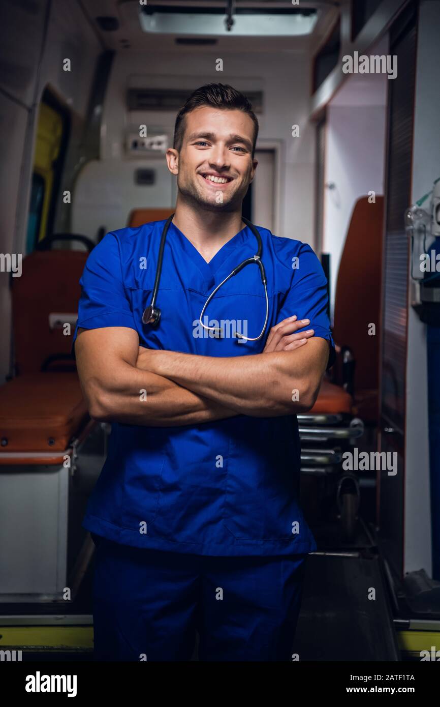 Doctor in blue medical uniform stands and looks at the camera with ...
