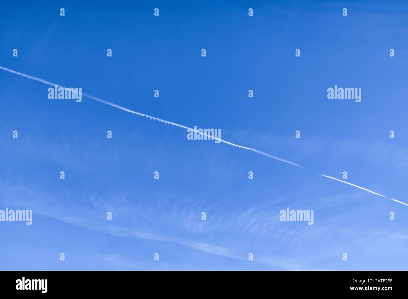 Chemtrail on slightly cloudy blue sky - background texture Stock Photo