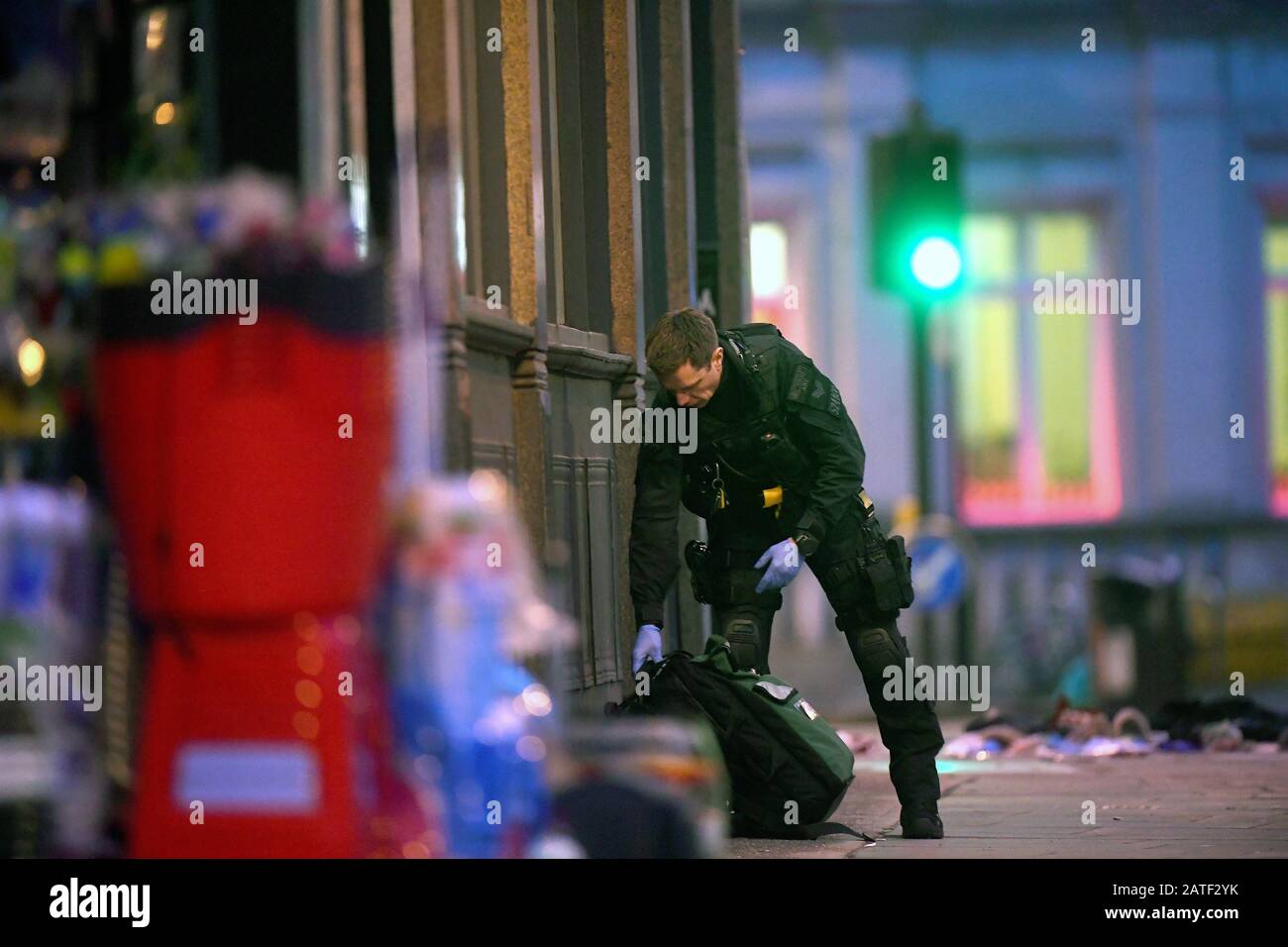 An armed police officer recovers medical bags at the scene in Streatham