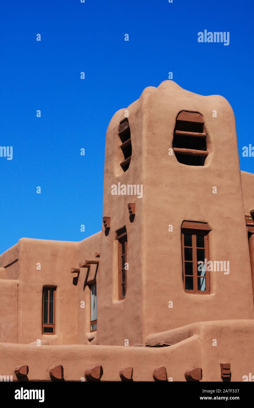 Pueblo adobe stucco stepped building. Contoured adobe plaster architecture with blue sky showing timber vigas. Santa Fe, New Mexico, Southwest USA Stock Photo