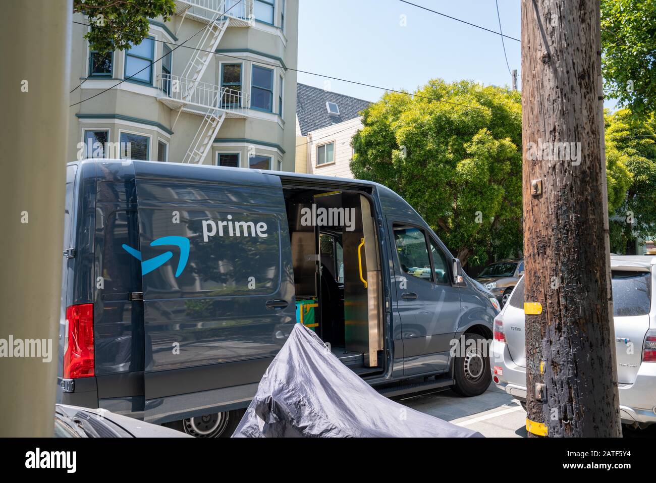Amazon prime delivery truck parked in neighborhood with driver going door to door Stock Photo