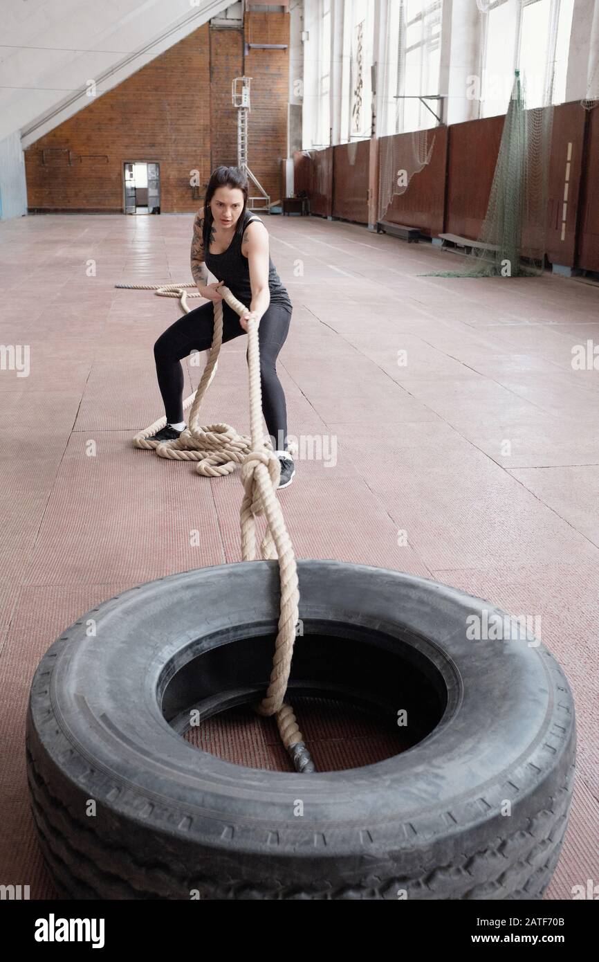 Young Caucasian female athlete pulling heavy tire with battle rope Stock Photo Alamy