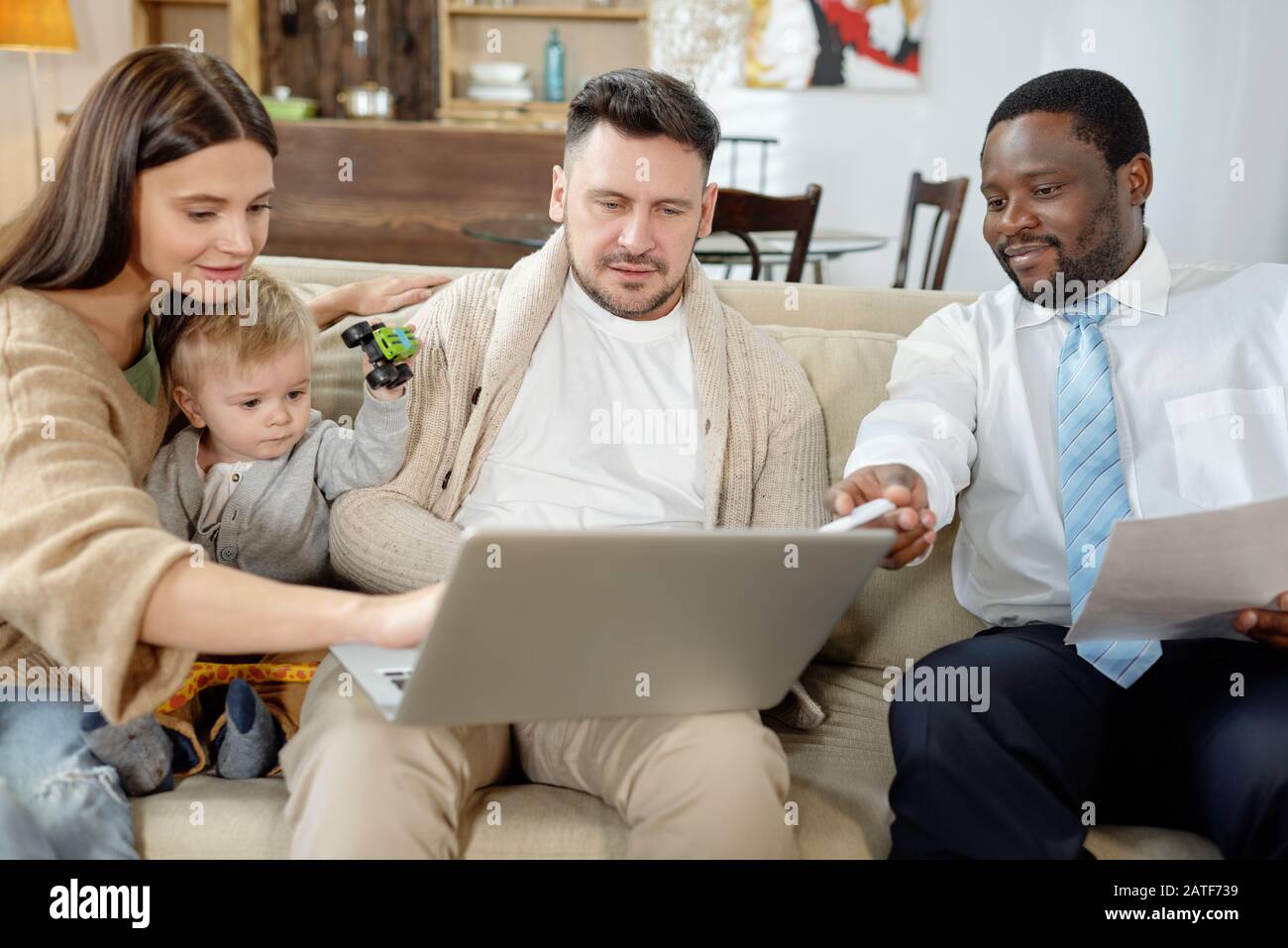 Ethnic consultant discussing real estate with young family Stock Photo