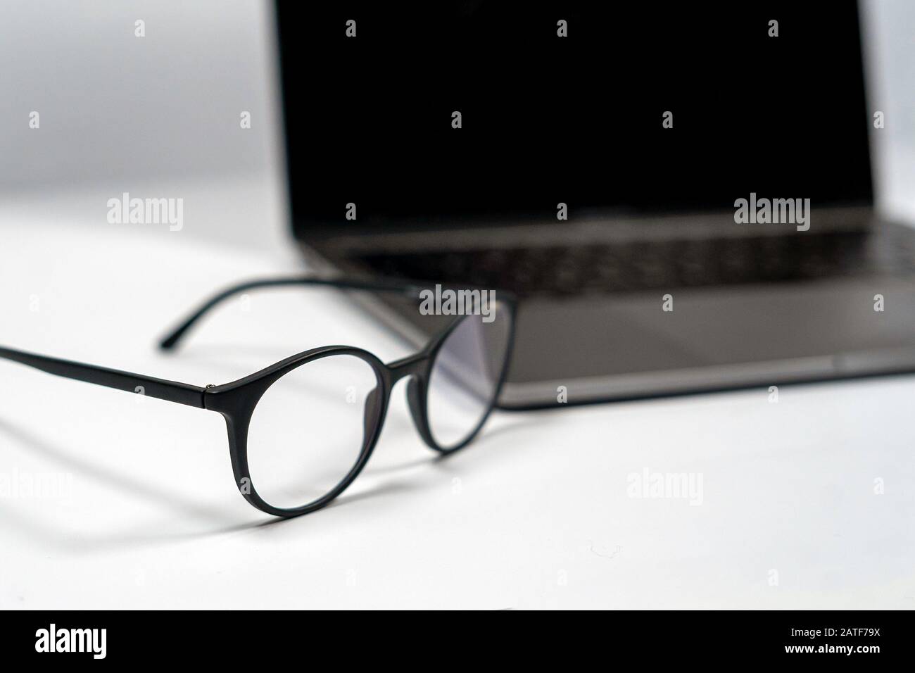 protective glasses on an empty desk with blurred computer screen on background Closeup Stock Photo