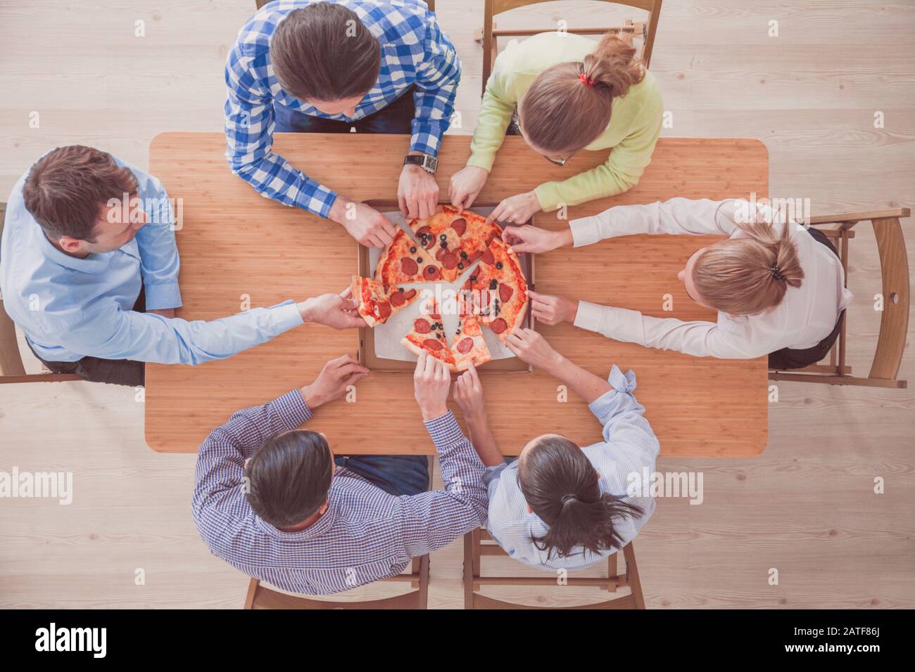 People taking pizza slices from wooden table, top view Stock Photo