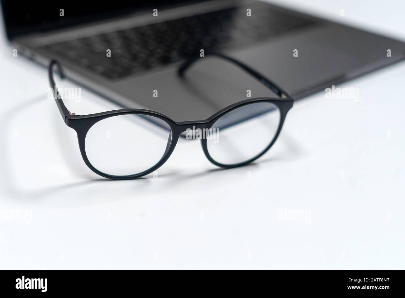 protective glasses on an empty desk with blurred computer screen on background Closeup Stock Photo