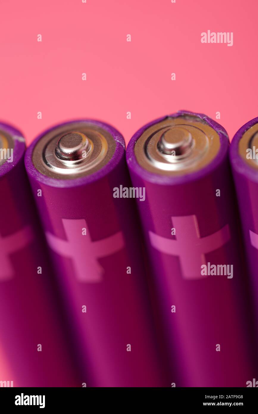 Four small batteries on a pink table. Stock Photo