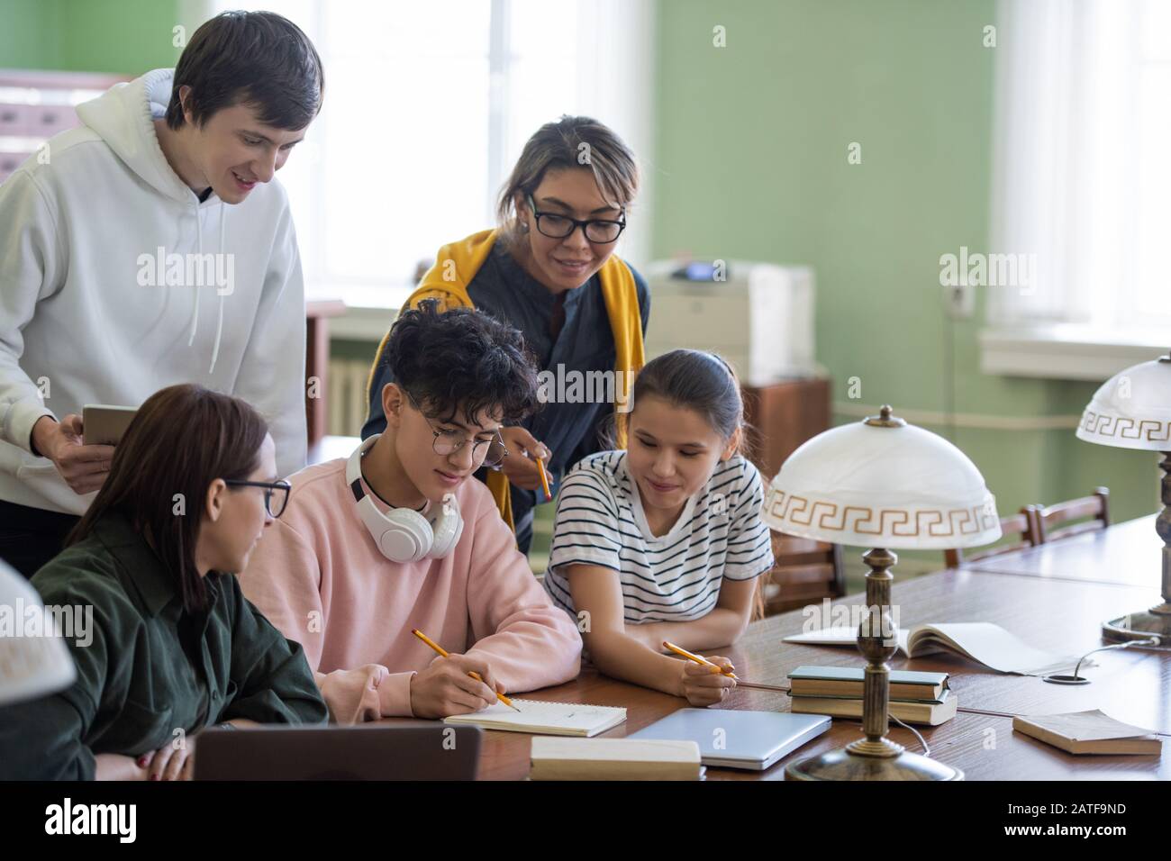 Two students pointing at notes of teenage guy while choosing name for(02)