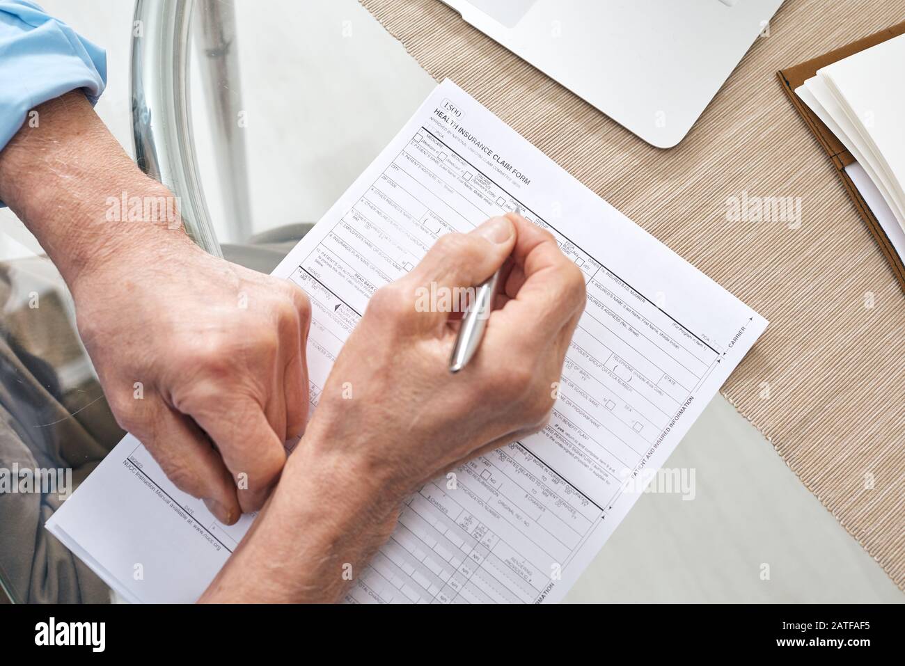 Hands of contemporary senior retired man filling in health insurance form Stock Photo