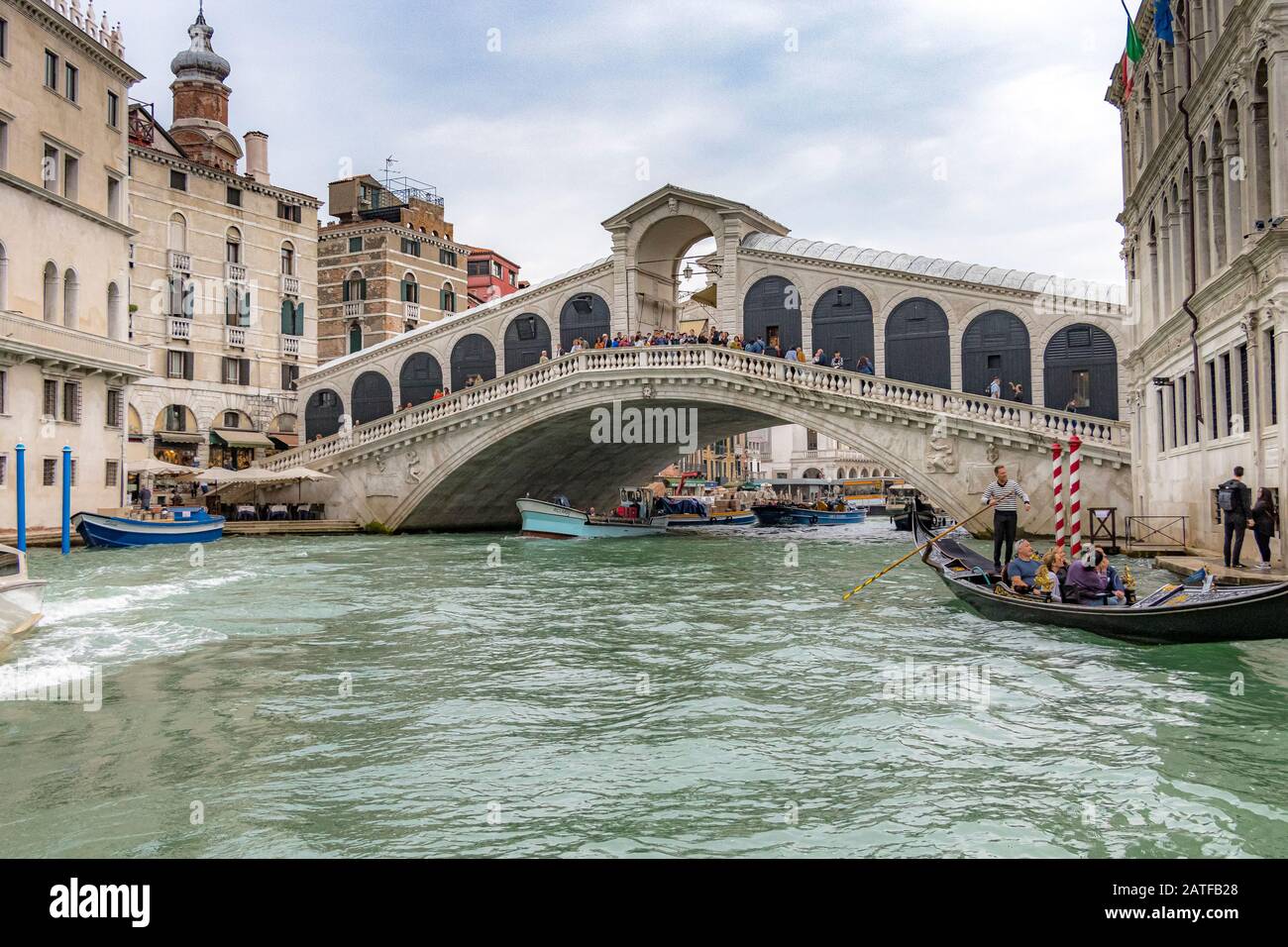A gondola with tourists taking a gondola ride in front of the Rialto Bridge, the oldest of four bridges crossing the Grand Canal in Venice ,Italy Stock Photo