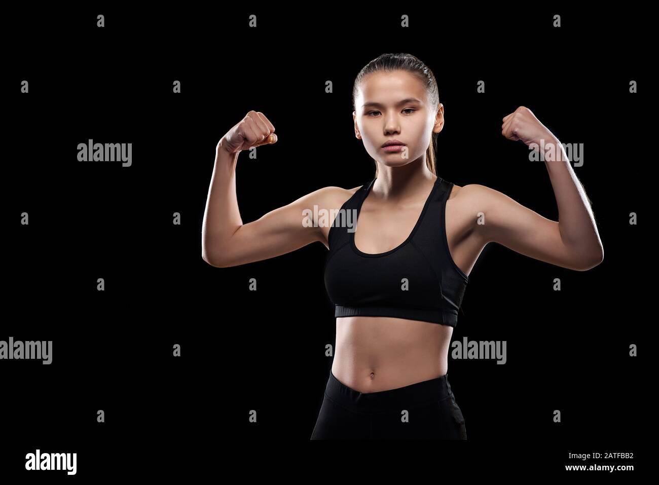 Serious sporty girl in black activewear standing in front of camera in