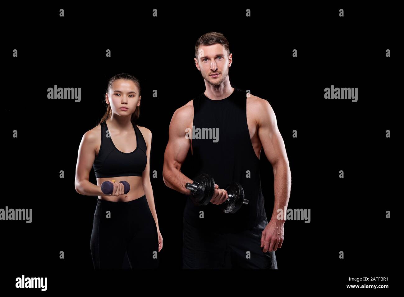Young fit woman with dumbbell and muscular sportsman with barbell Stock Photo