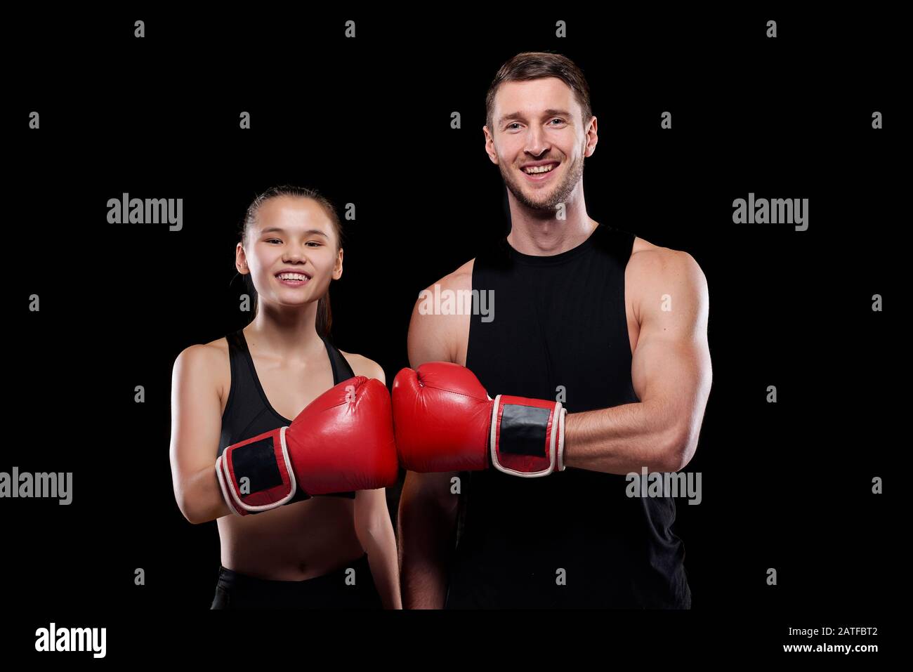 Happy man and woman in activewear touching each other hands in boxing