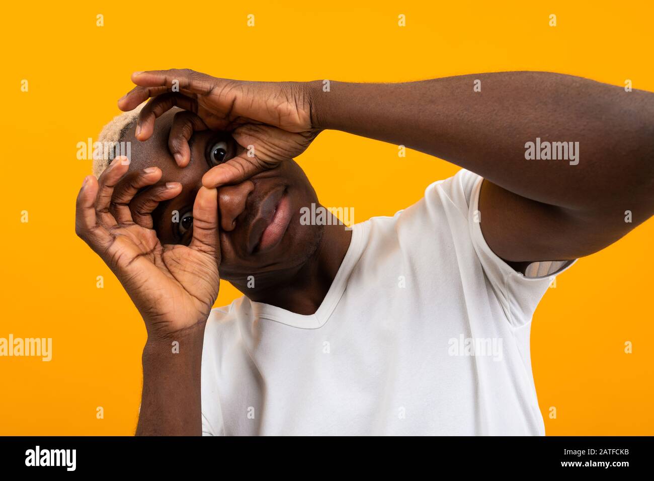 surprised black african young man covers his face with his hands and ...