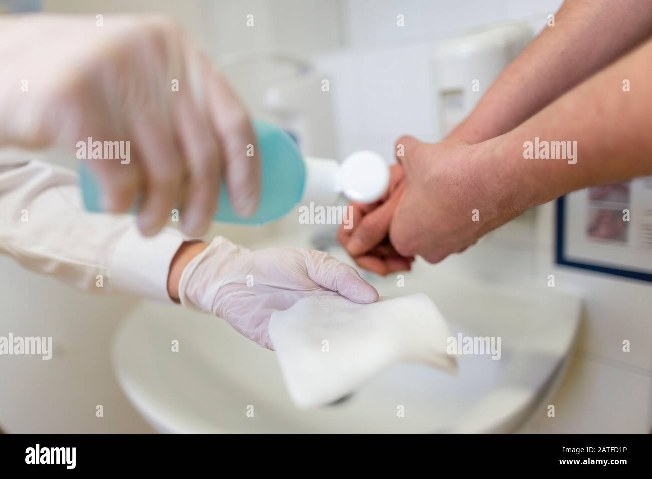 Nurse disinfects a patients hand at a sink Stock Photo