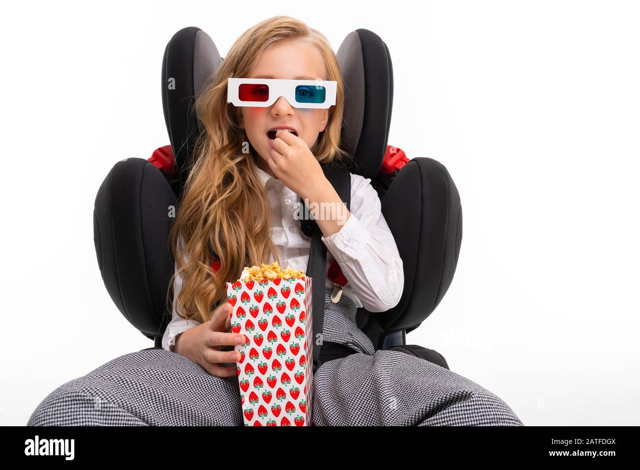 A little girl with makeup and long blonde hair sits on a car baby chair and  looks film or cartoon with popcorn isolated on white background Stock Photo  - Alamy