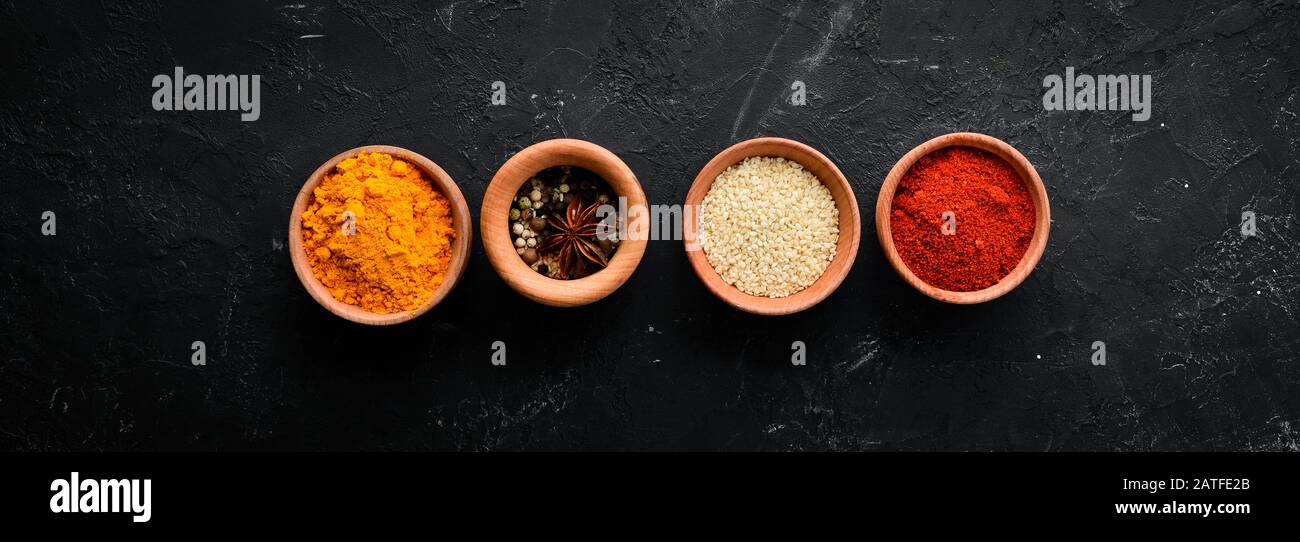 Colored spices on a black stone background. Free space for your text. Top view. Stock Photo