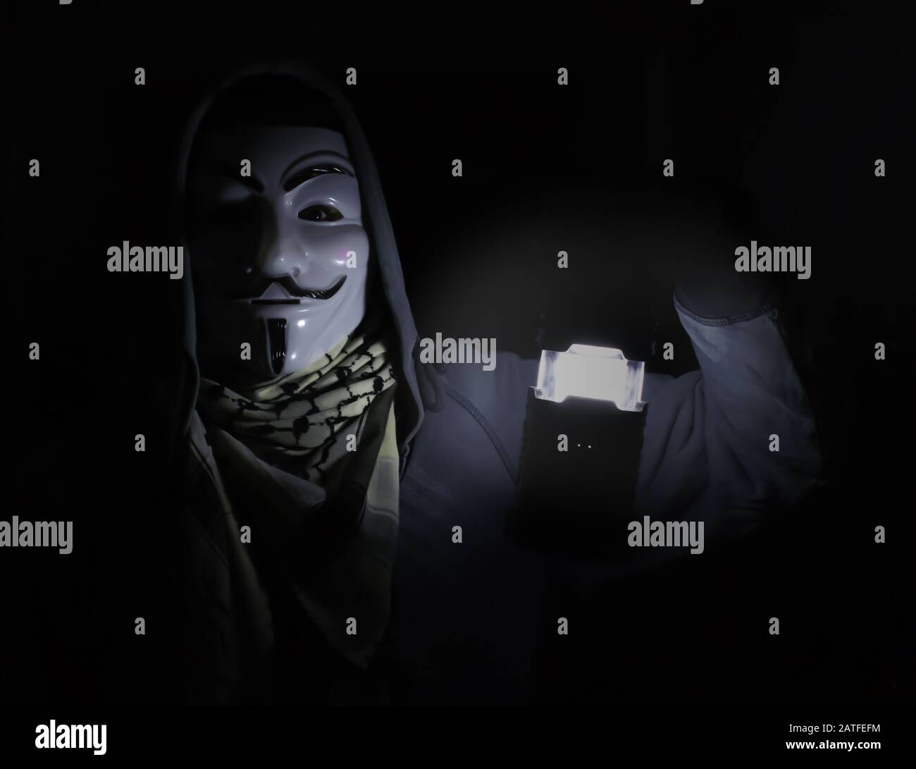person wearing guy fawkes mask in obscurity Stock Photo