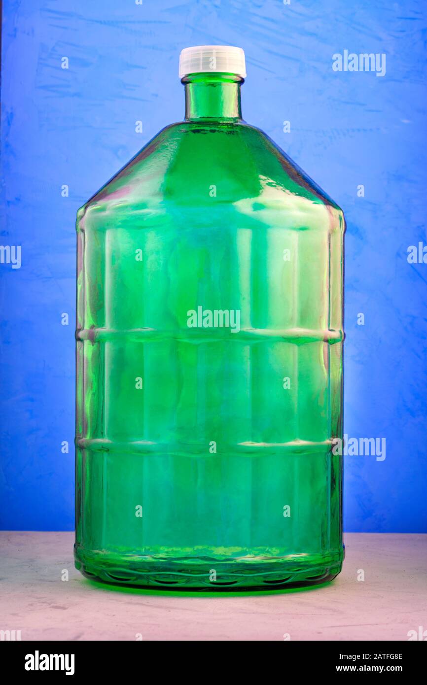 A 22 liter glass jar is made of thick green glass, image on a blue
