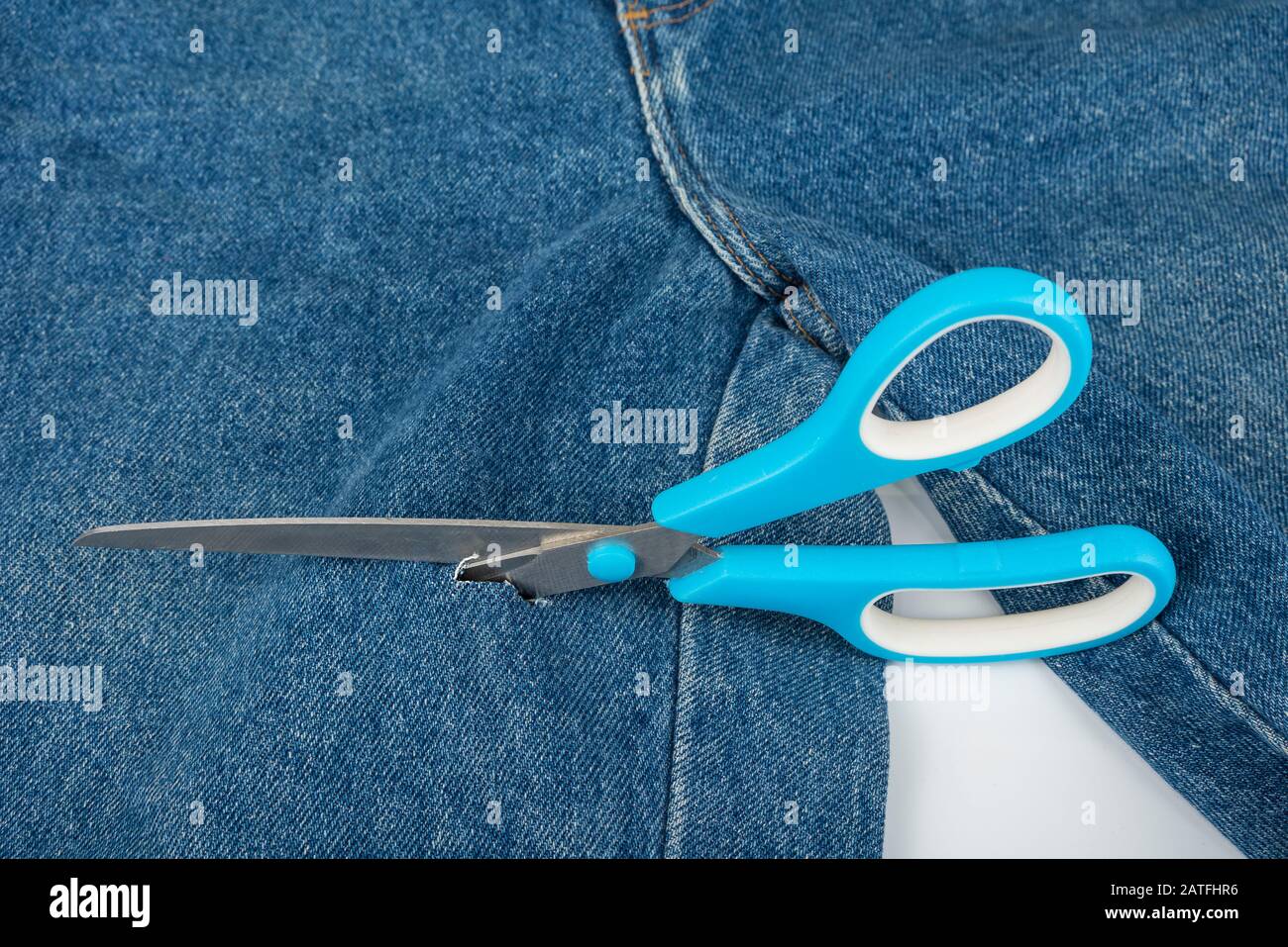 Make a hole in blue jeans with scissors Stock Photo Alamy
