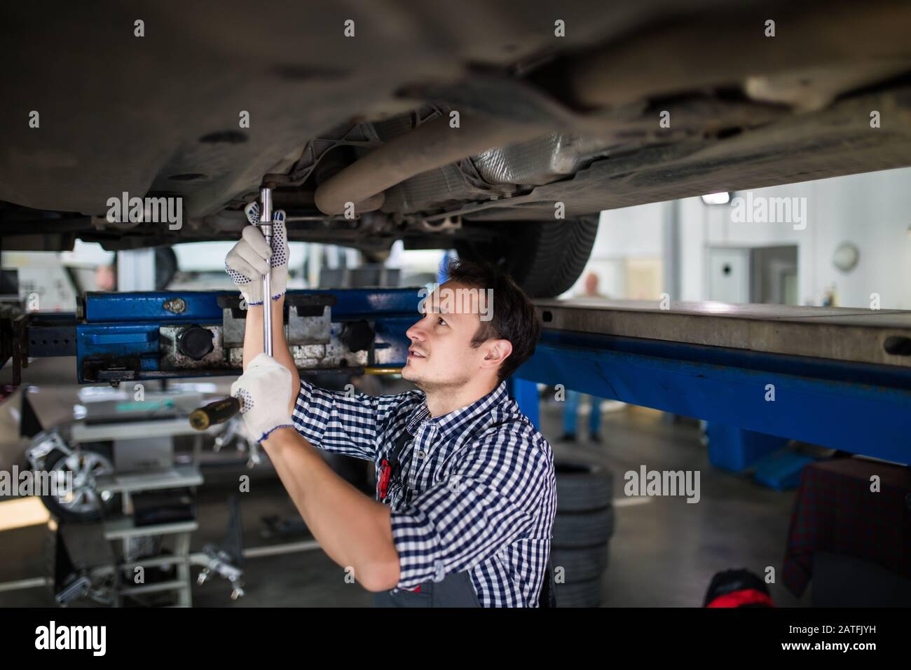 Male And Female Mechanics Working Underneath Car Together Stock Photo