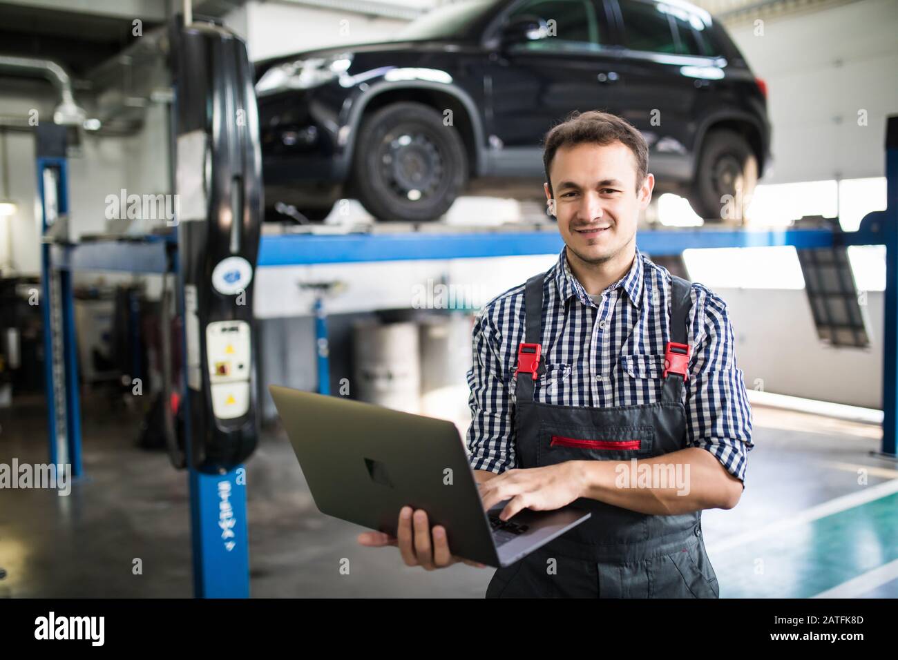 Mechanic using computer diagnostics while repairing car Stock Photo