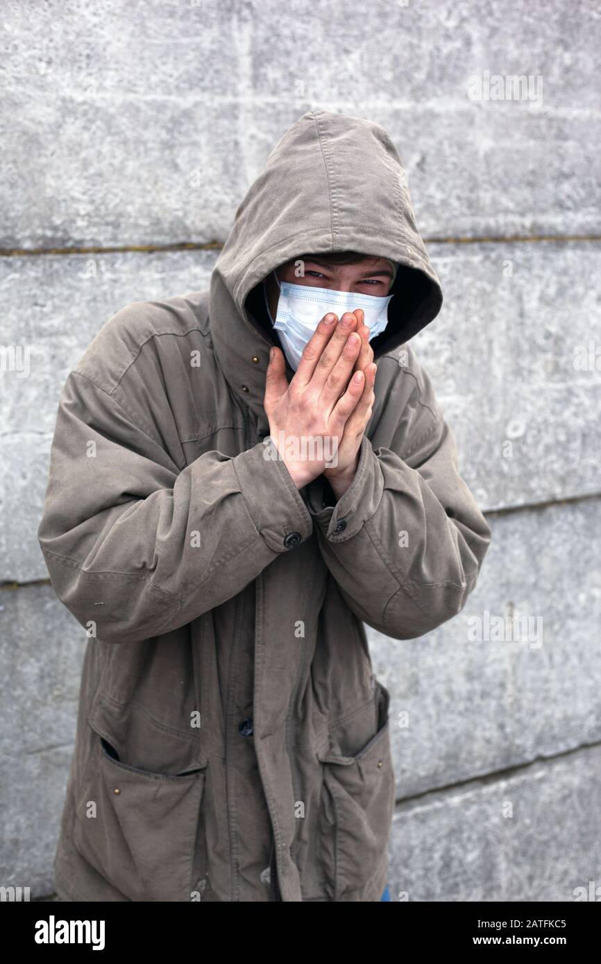 sick homeless in a medical mask caught a cold. Stock Photo