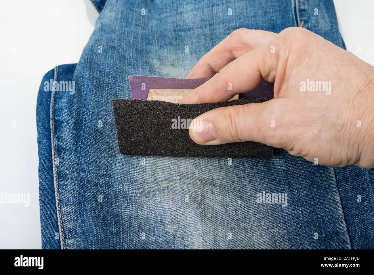 Make blue jeans look worn out by sanding Stock Photo