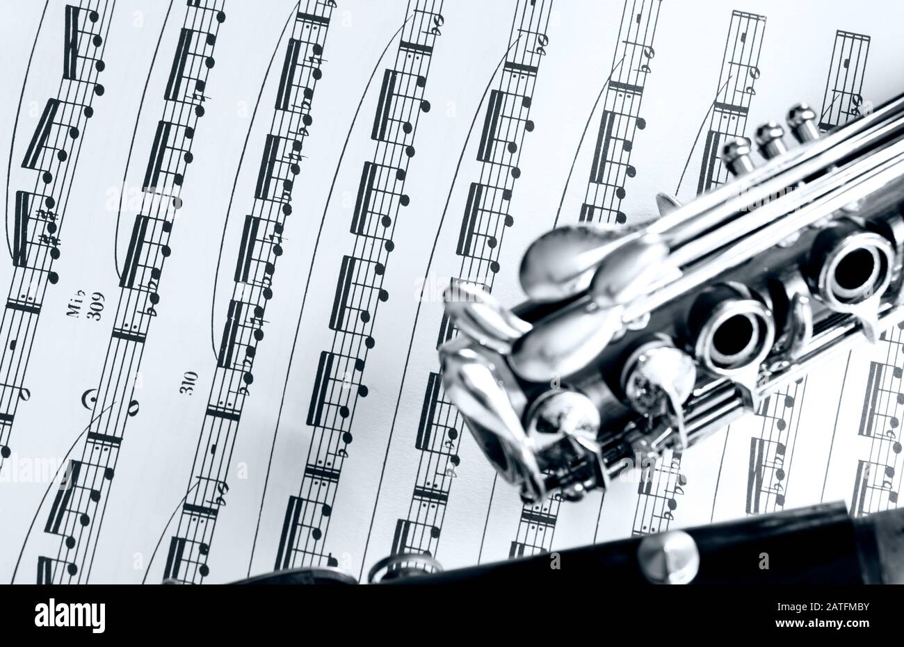 part of the clarinet body on a partiture with printed notes Stock Photo